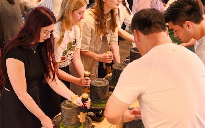 Tourists grinding tencha leaves into matcha powder at Chazuna Museum, Uji, Kyoto.