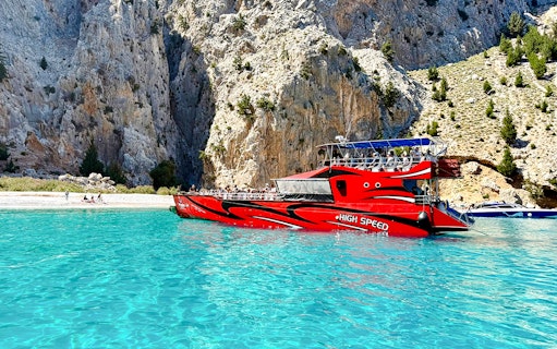 High-speed boat near rocky cliffs in St George's Bay, Rhodes.