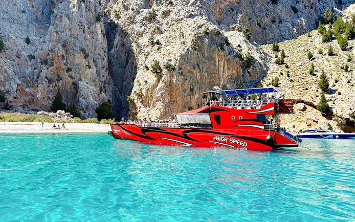 High-speed boat near rocky cliffs in St George's Bay, Rhodes.