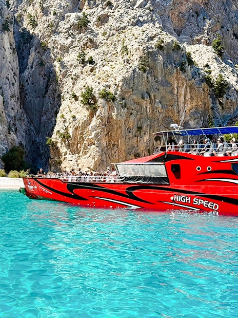 High-speed boat near rocky cliffs in St George's Bay, Rhodes.