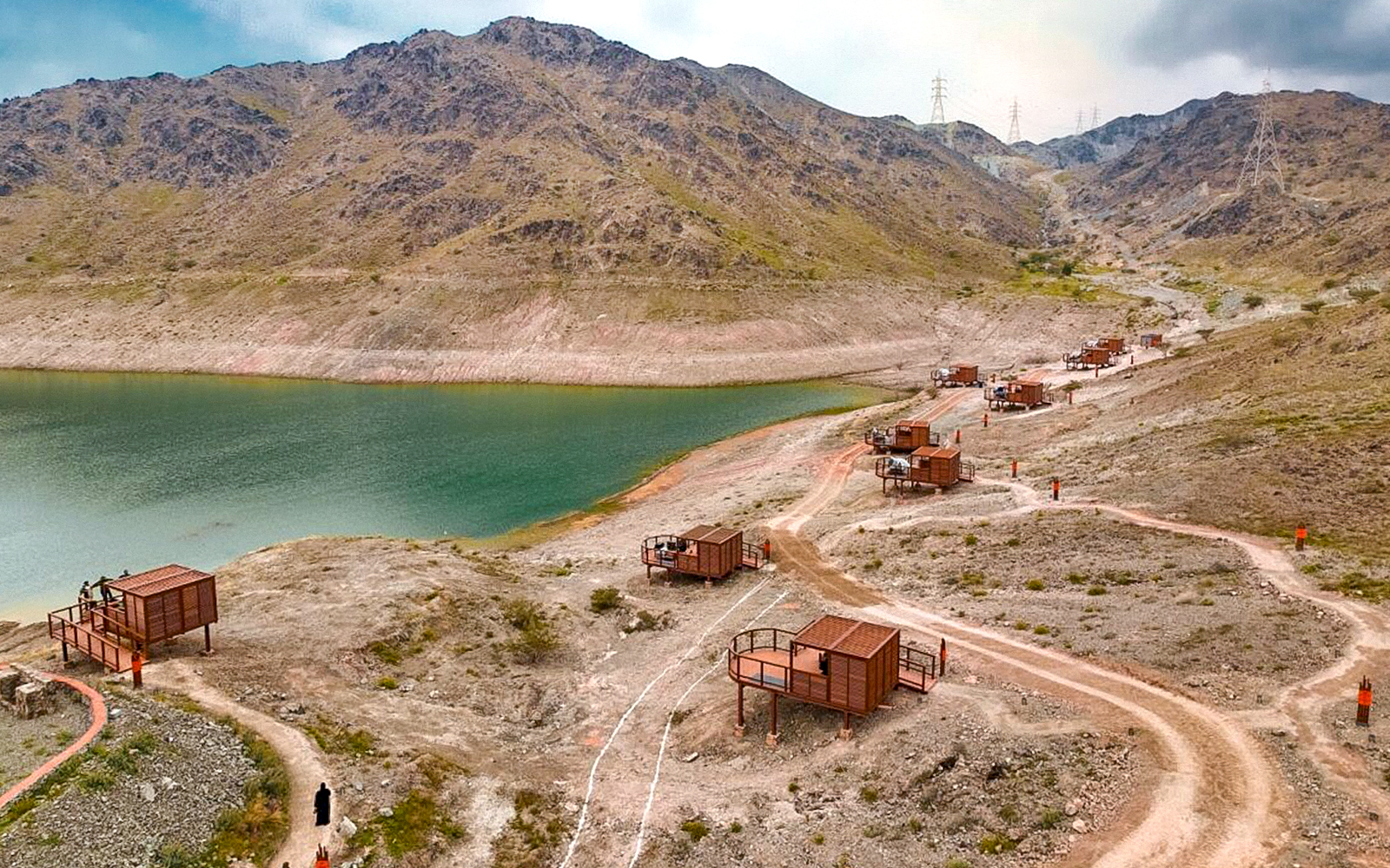 Fujairah Adventure Park cabins along a mountain trail by a lake.