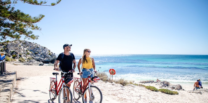 Couple with bicycles on Rottnest Island beach, Western Australia.
