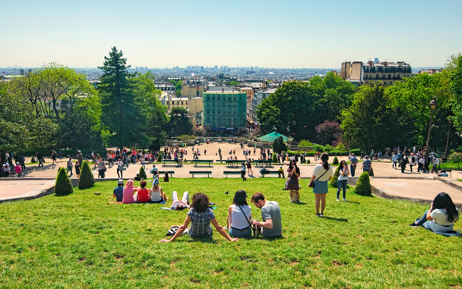 View from Montmartre hill of Sacre Coeur with tourists on the lawn, Paris.