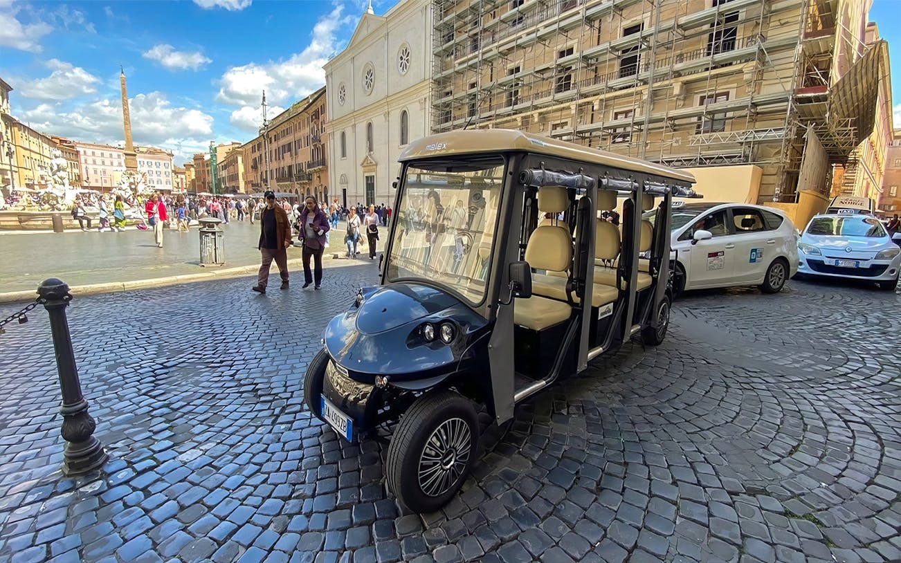 Golf cart parked in Piazza Navona, Rome, with tourists and historic architecture in the background.
