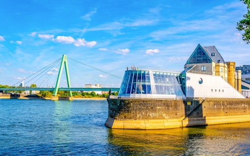 Chocolate Museum in Cologne by the Rhine River with a bridge in the background.
