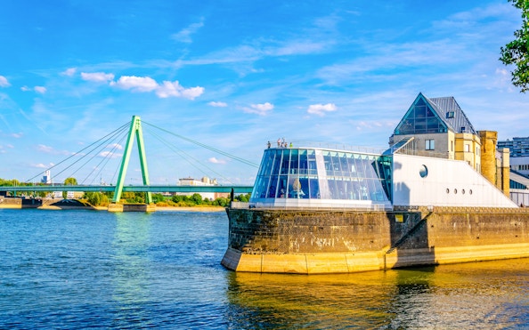 Chocolate Museum in Cologne by the Rhine River with a bridge in the background.