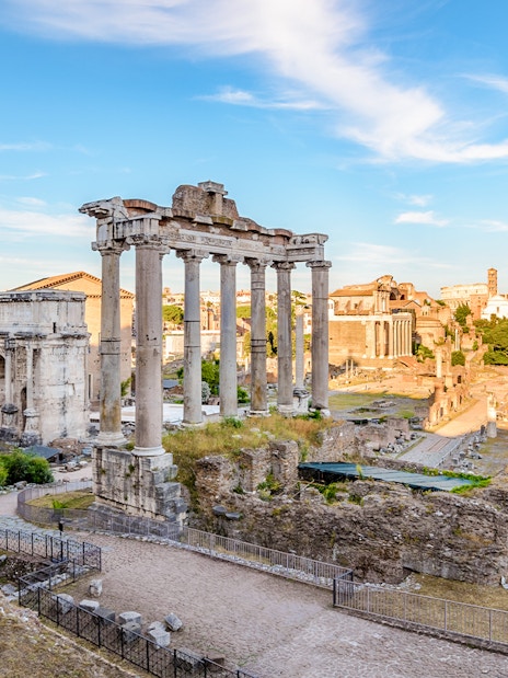 Roman Forum ruins with ancient columns and arches in Rome, Italy.