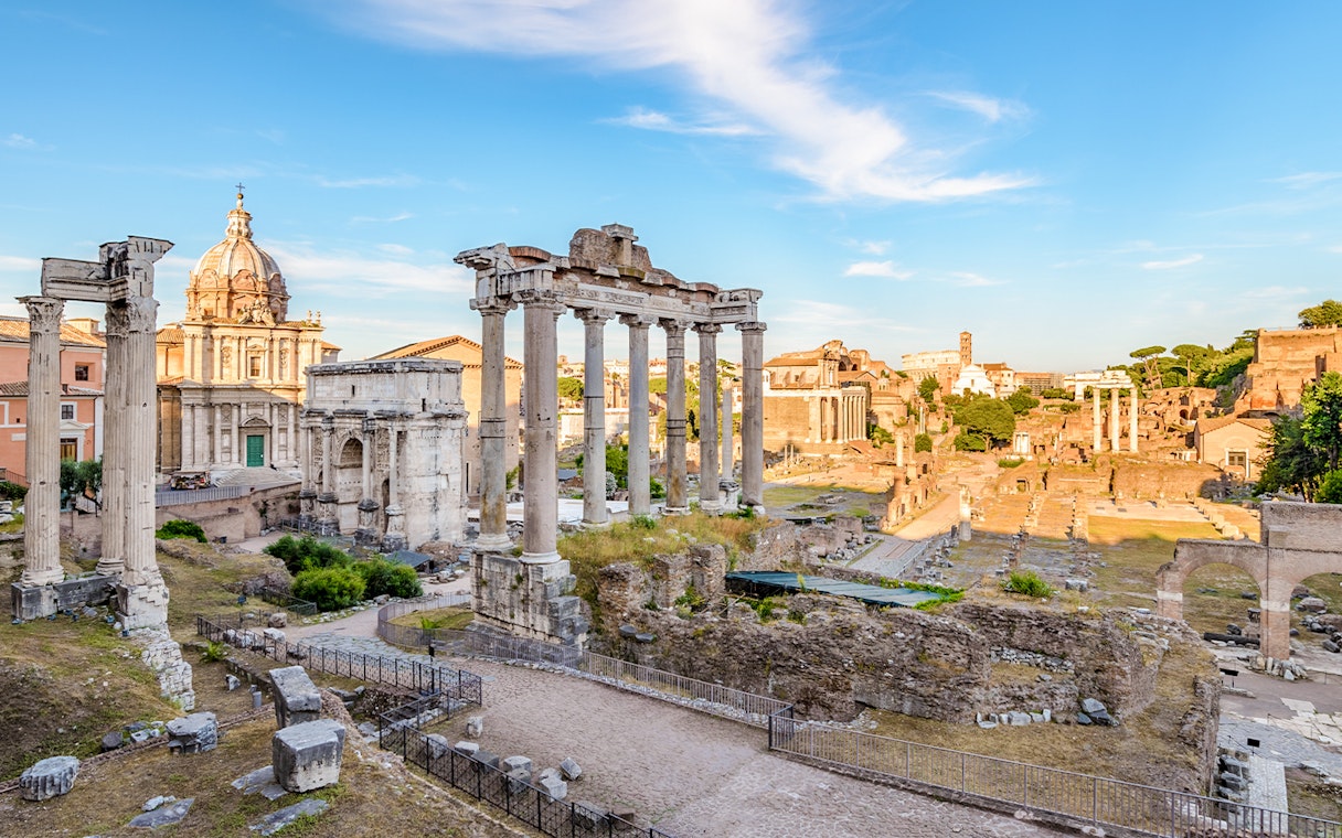 Roman Forum ruins with ancient columns and arches in Rome, Italy.