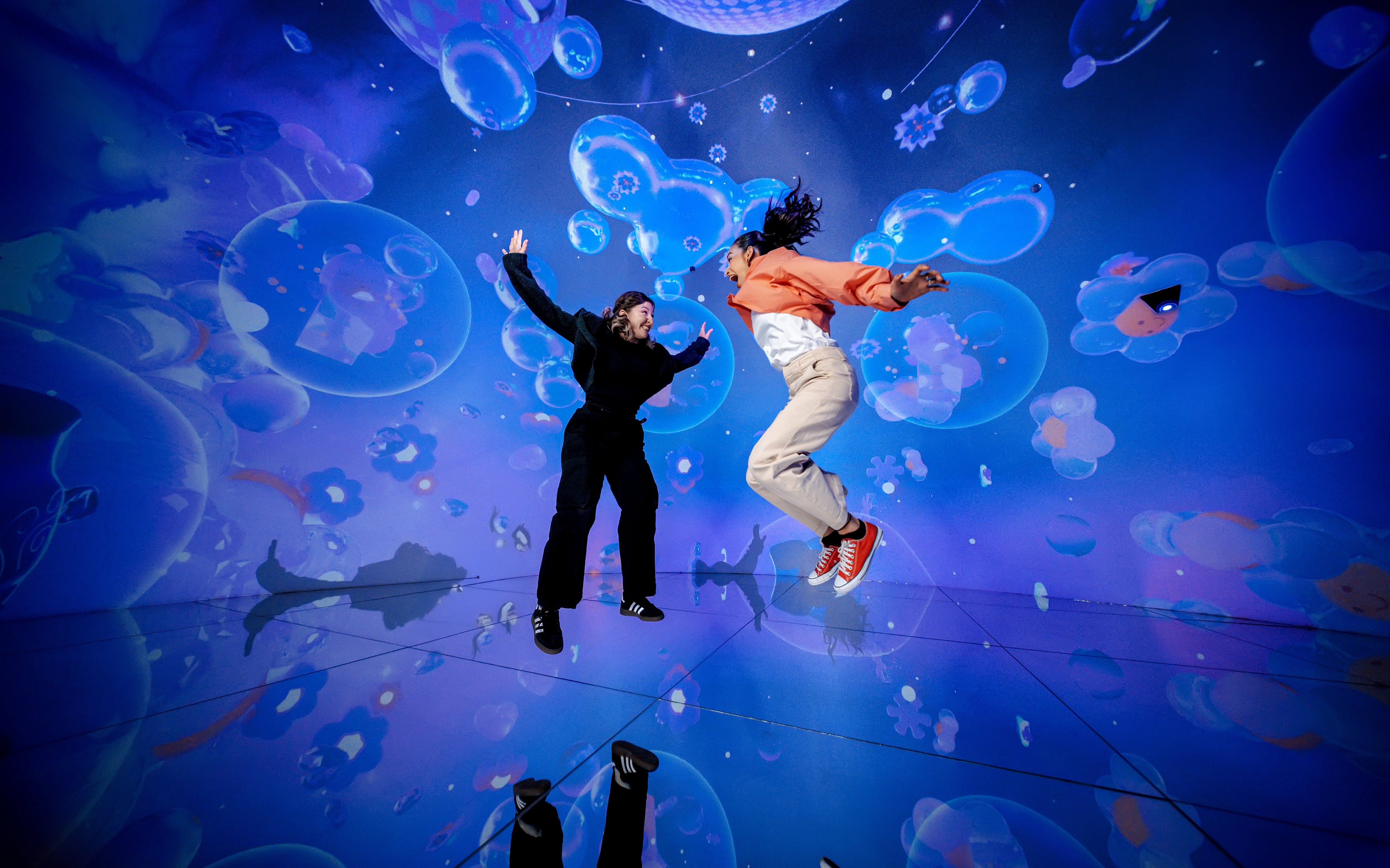 People jumping in a vibrant digital art installation at House Of Hype.