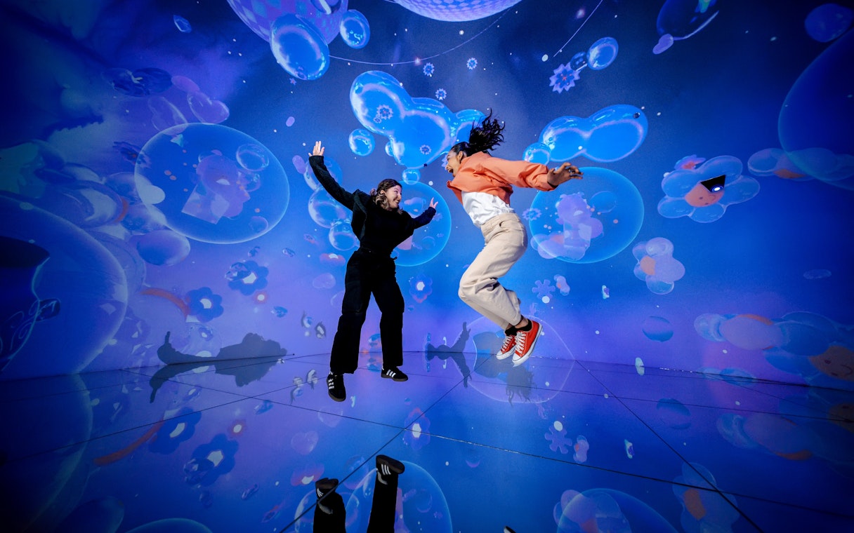 People jumping in a vibrant digital art installation at House Of Hype.