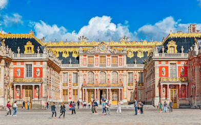Main entrance of Palace of Versailles with visitors exploring the courtyard.