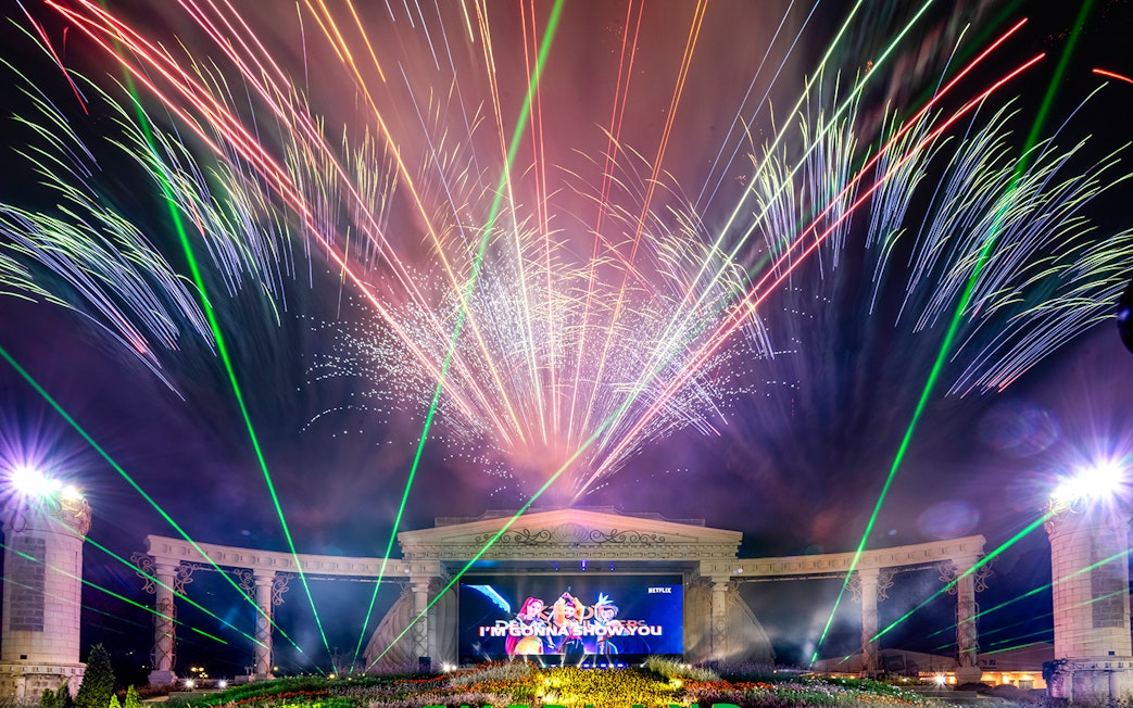 Fireworks display at K-pop demon hunters event with colorful lights and stage.