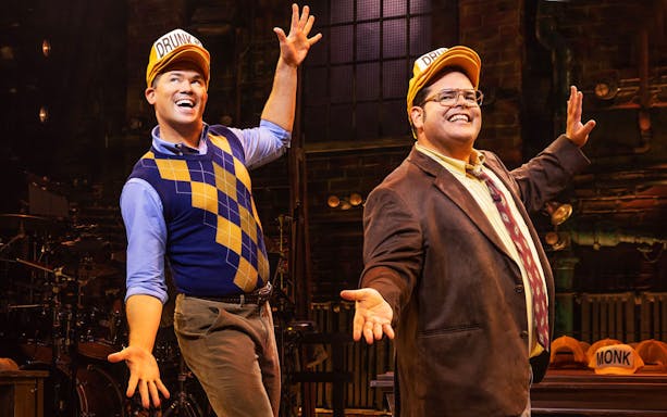 Actors performing in "Gutenberg! The Musical!" on stage with expressive gestures.