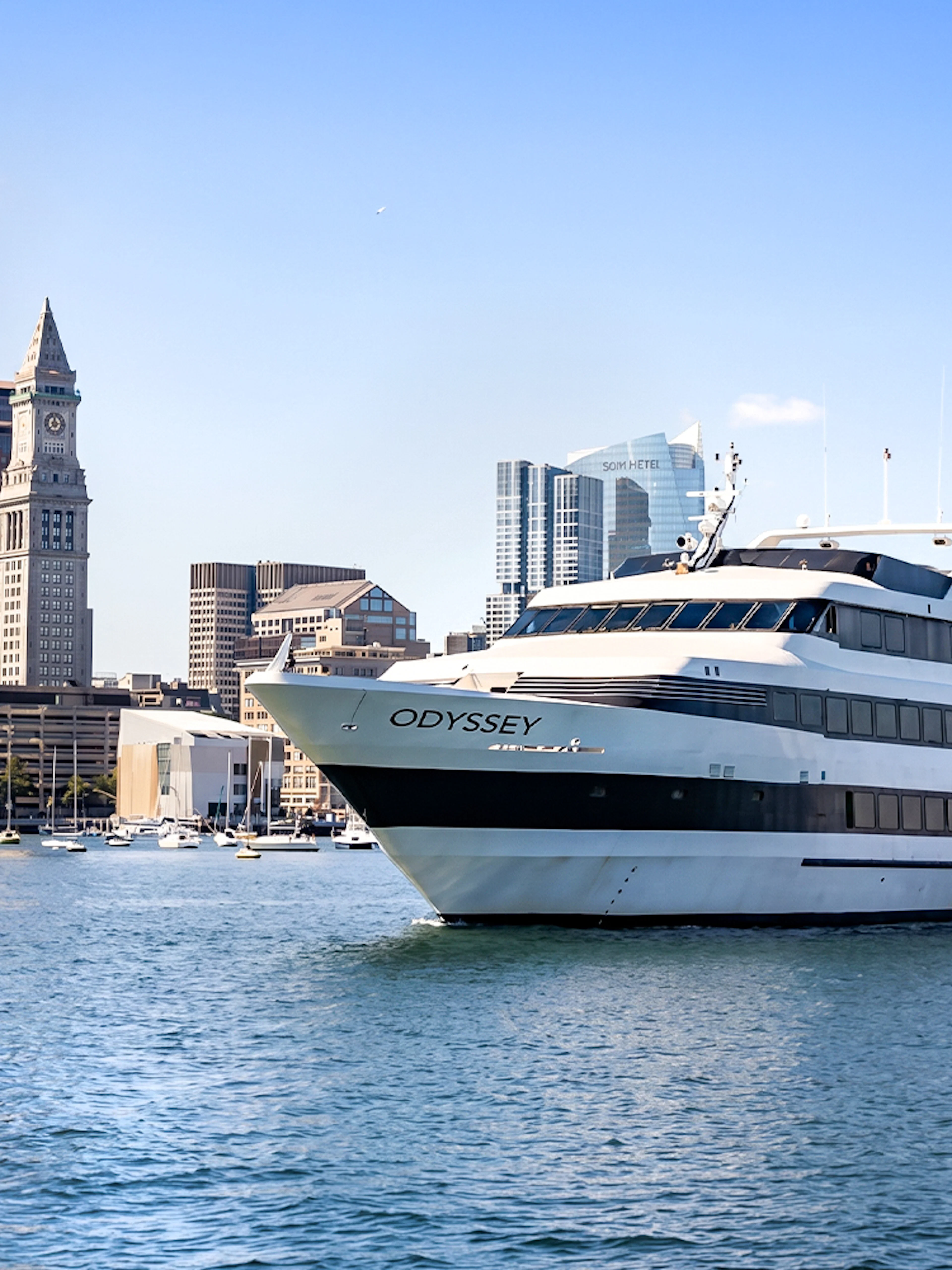 Cruise ship on Boston Harbor with city skyline in the background.