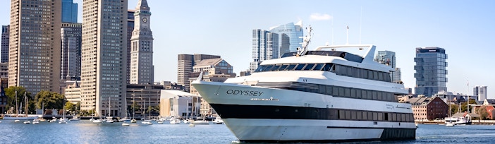 Cruise ship on Boston Harbor with city skyline in the background.