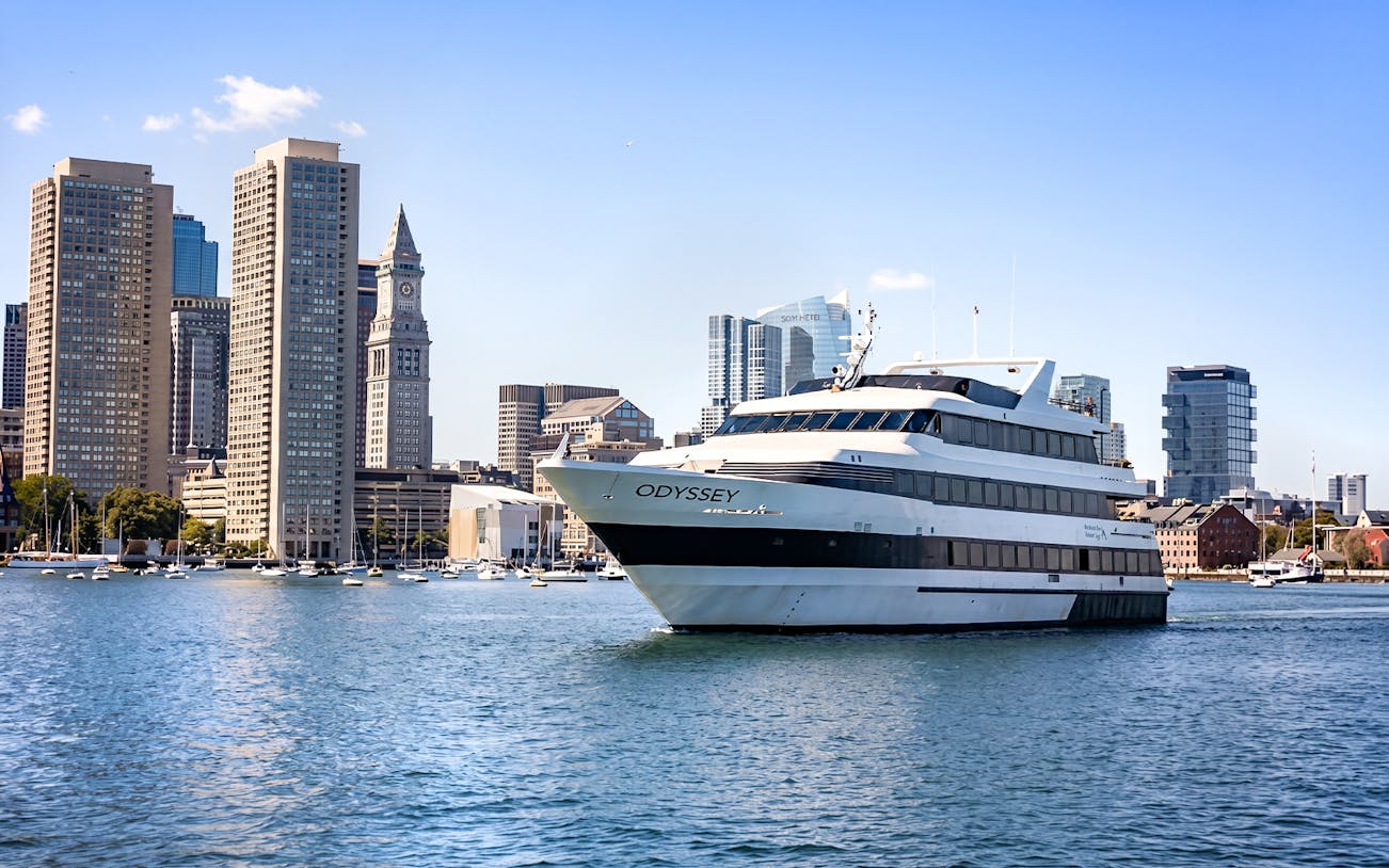 Cruise ship on Boston Harbor with city skyline in the background.