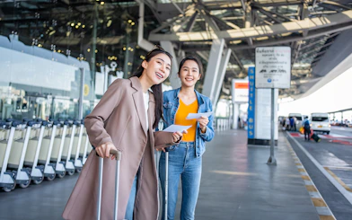 Travelers with luggage at Girona Airport shuttle bus area.