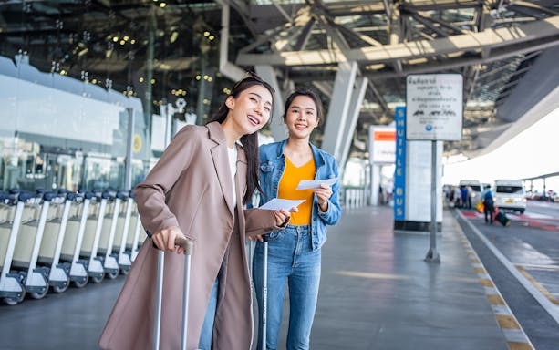 Travelers with luggage at Girona Airport shuttle bus area.