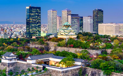 Osaka skyline with Osaka Castle and modern buildings at dusk.