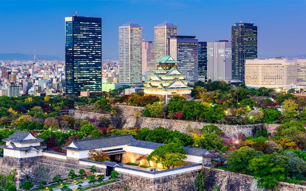 Osaka skyline with Osaka Castle and modern buildings at dusk.
