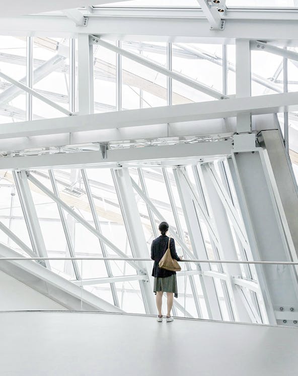 Person standing inside Fondation Louis Vuitton, Paris, viewing modern architectural design.