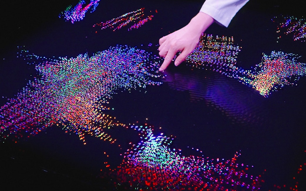 Interactive digital art display at Team Lab Abu Dhabi with colorful lights and hand interaction.