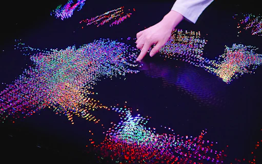 Interactive digital art display at Team Lab Abu Dhabi with colorful lights and hand interaction.