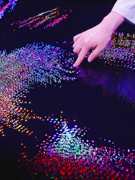 Interactive digital art display at Team Lab Abu Dhabi with colorful lights and hand interaction.