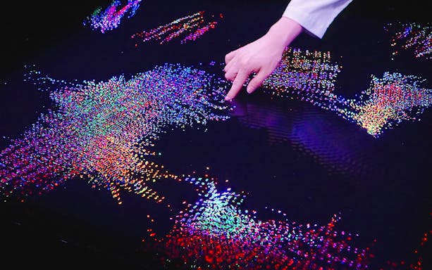 Interactive digital art display at Team Lab Abu Dhabi with colorful lights and hand interaction.