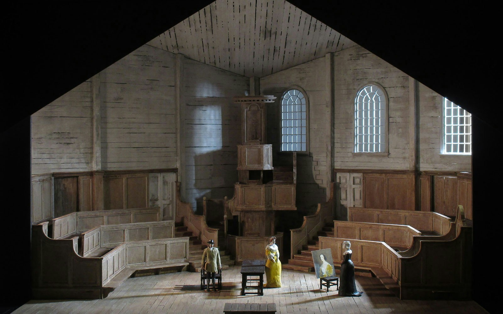 Stage set of "I Puritani" with figures in period costumes in a wooden interior.