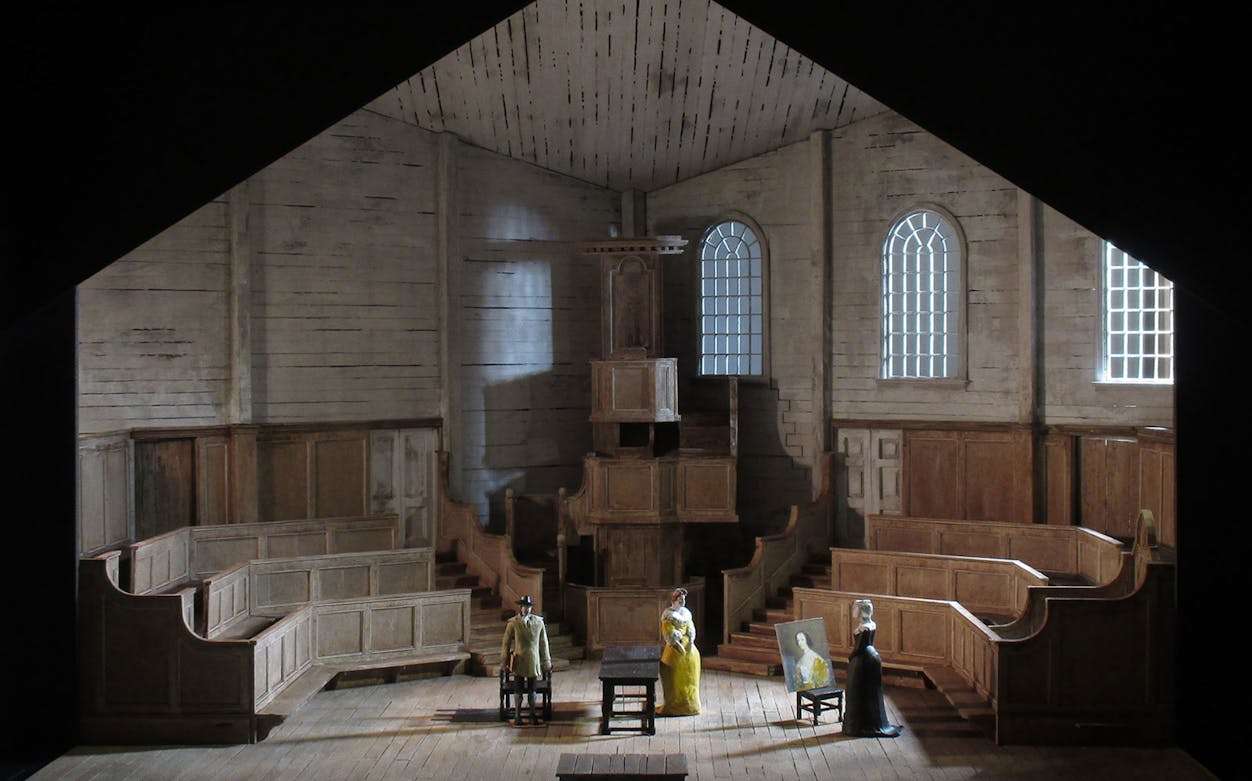 Stage set of "I Puritani" with figures in period costumes in a wooden interior.