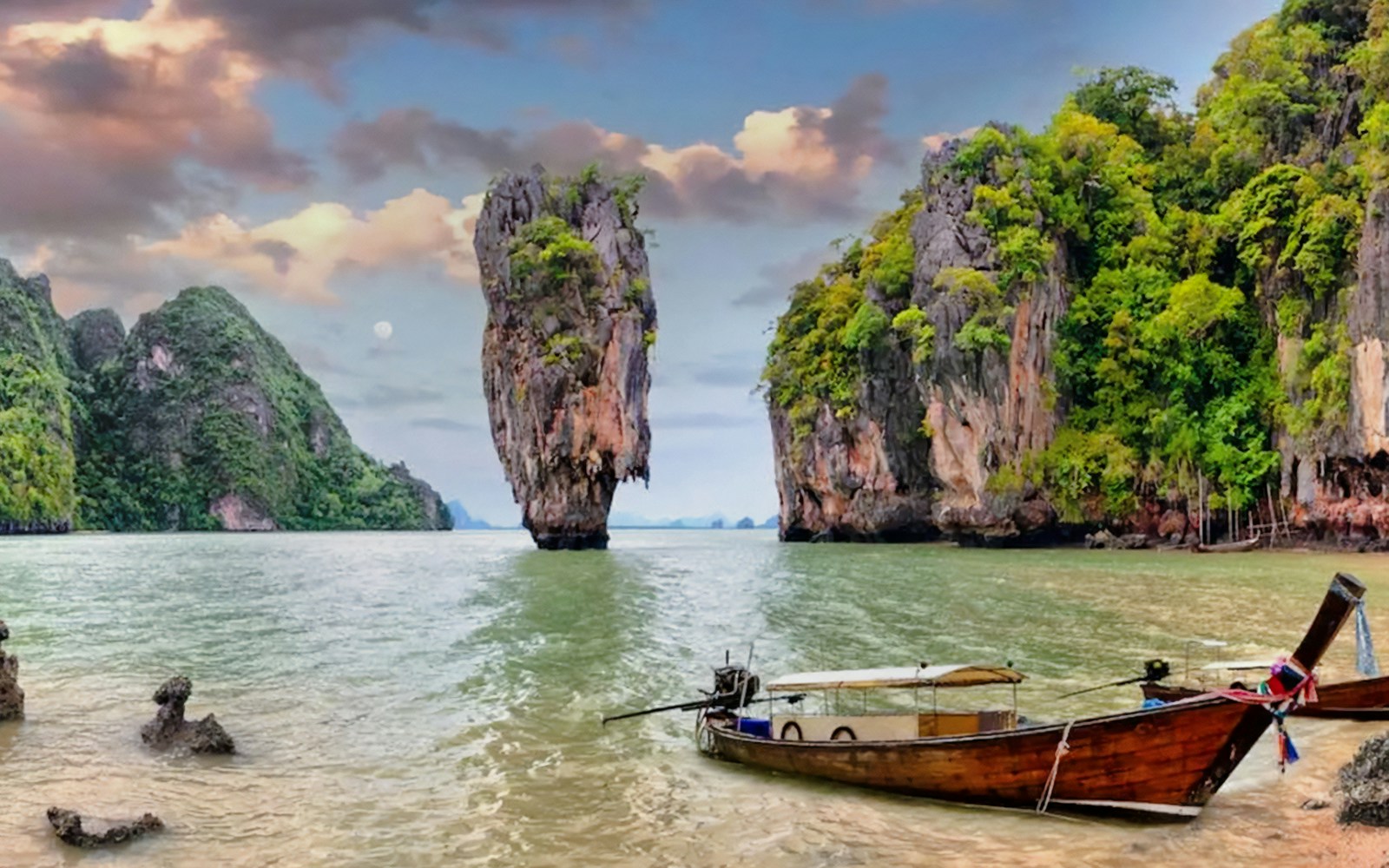 Panoramic view of James Bond Island with a traditional longtail boat in the foreground.