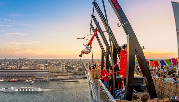 Tourists on swing ride at A'DAM LOOKOUT with Amsterdam skyline in the background.