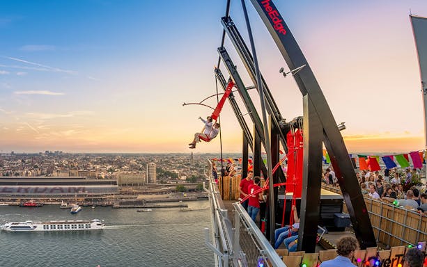 Tourists on swing ride at A'DAM LOOKOUT with Amsterdam skyline in the background.