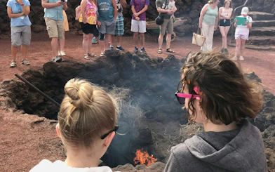 Visitors watch volcanic heat demonstration at Islote de Hilario, Timanfaya National Park, Lanzarote.
