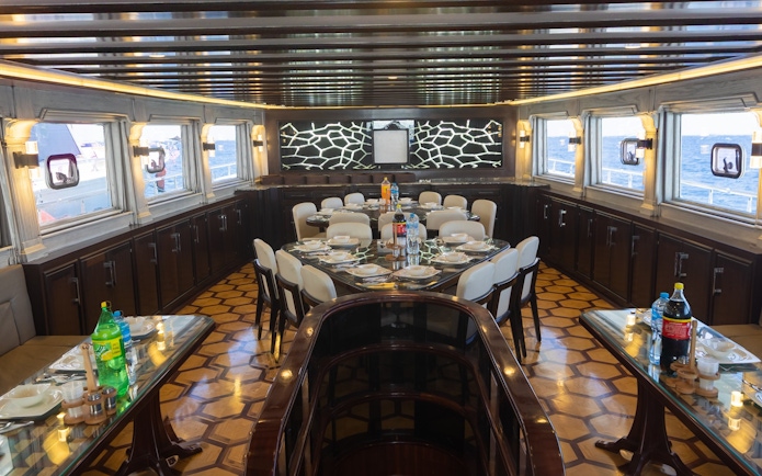 Interior saloon and dining area of a yacht, Orange Bay Island, Hurghada, with set dining tables.