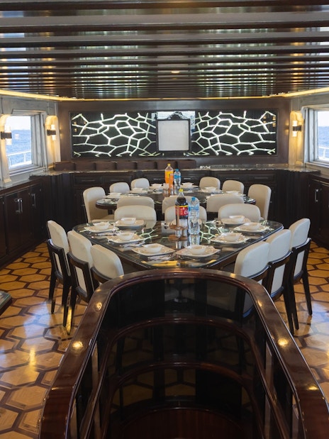 Interior saloon and dining area of a yacht, Orange Bay Island, Hurghada, with set dining tables.