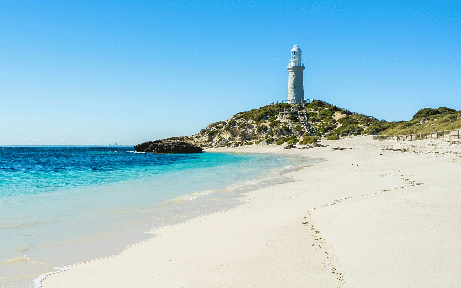 Lighthouse on Pink Beach, Rottnest Island, with clear blue water and sandy shore.
