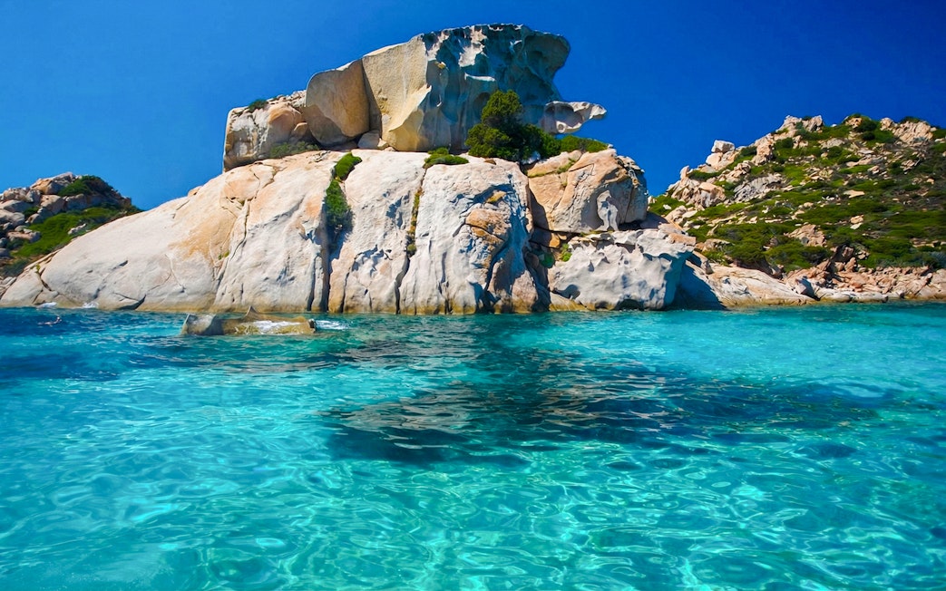 Sailing near rocky coastline in La Maddalena Archipelago, Sardinia.