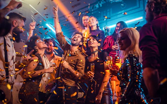 New Year's Eve party on a boat near Ain Dubai with people celebrating and confetti falling.