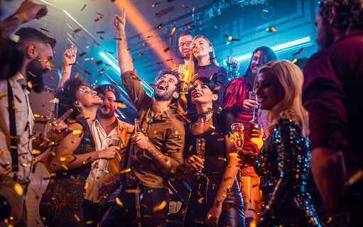New Year's Eve party on a boat near Ain Dubai with people celebrating and confetti falling.