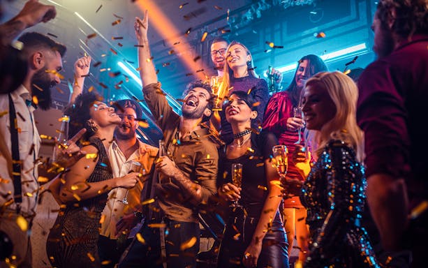 New Year's Eve party on a boat near Ain Dubai with people celebrating and confetti falling.