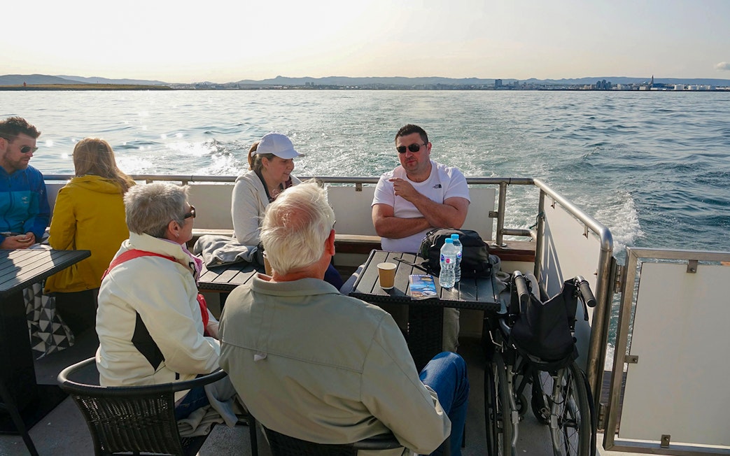 Guests enjoying hot drinks on a luxury yacht during a whale watching tour.