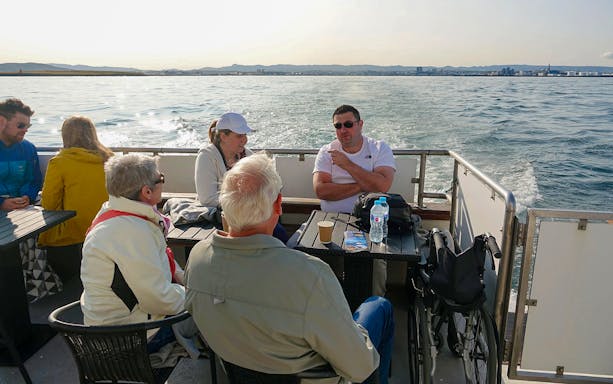 Guests enjoying hot drinks on a luxury yacht during a whale watching tour.