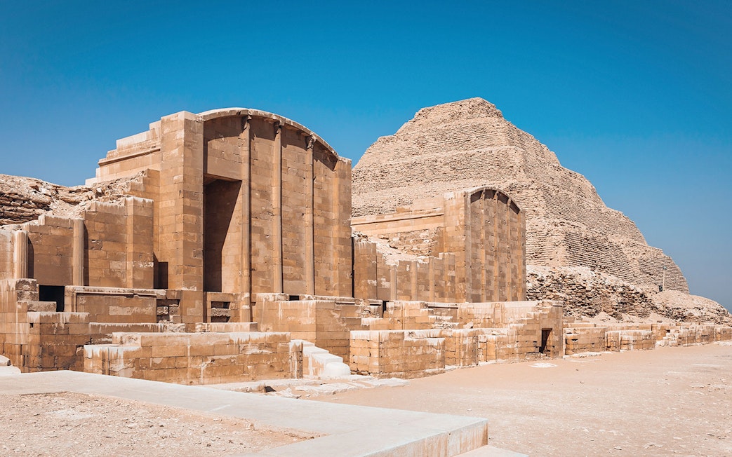 Sakkara Pyramid complex with ancient stone structures under a clear blue sky.