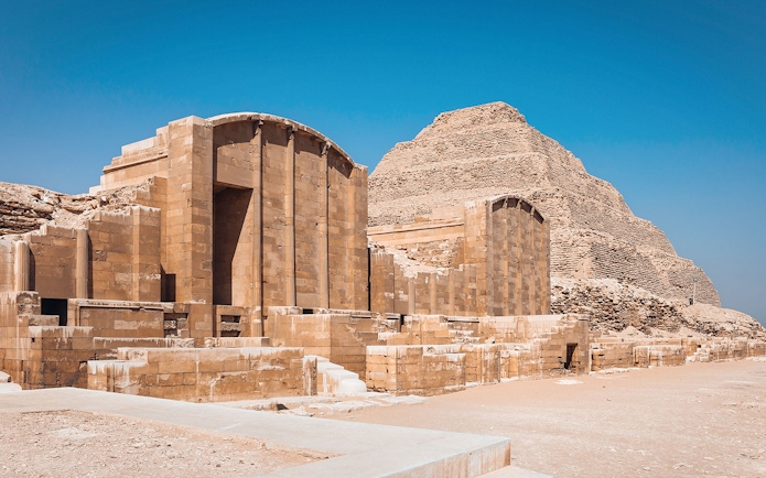Sakkara Pyramid complex with ancient stone structures under a clear blue sky.