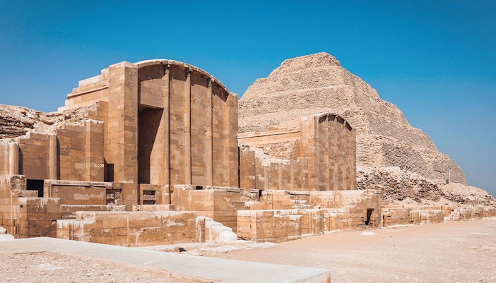 Sakkara Pyramid complex with ancient stone structures under a clear blue sky.