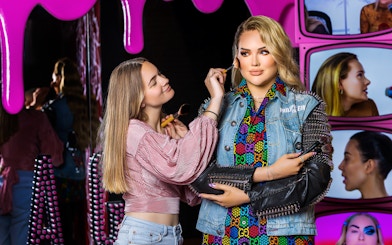 Makeup artist applying blush to wax figure at Madame Tussauds Amsterdam.