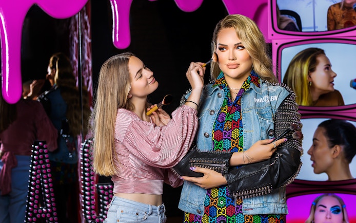 Makeup artist applying blush to wax figure at Madame Tussauds Amsterdam.