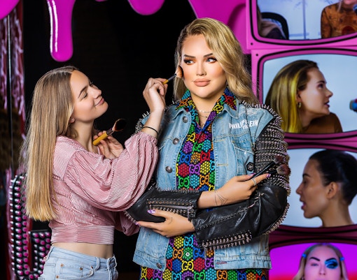 Makeup artist applying blush to wax figure at Madame Tussauds Amsterdam.